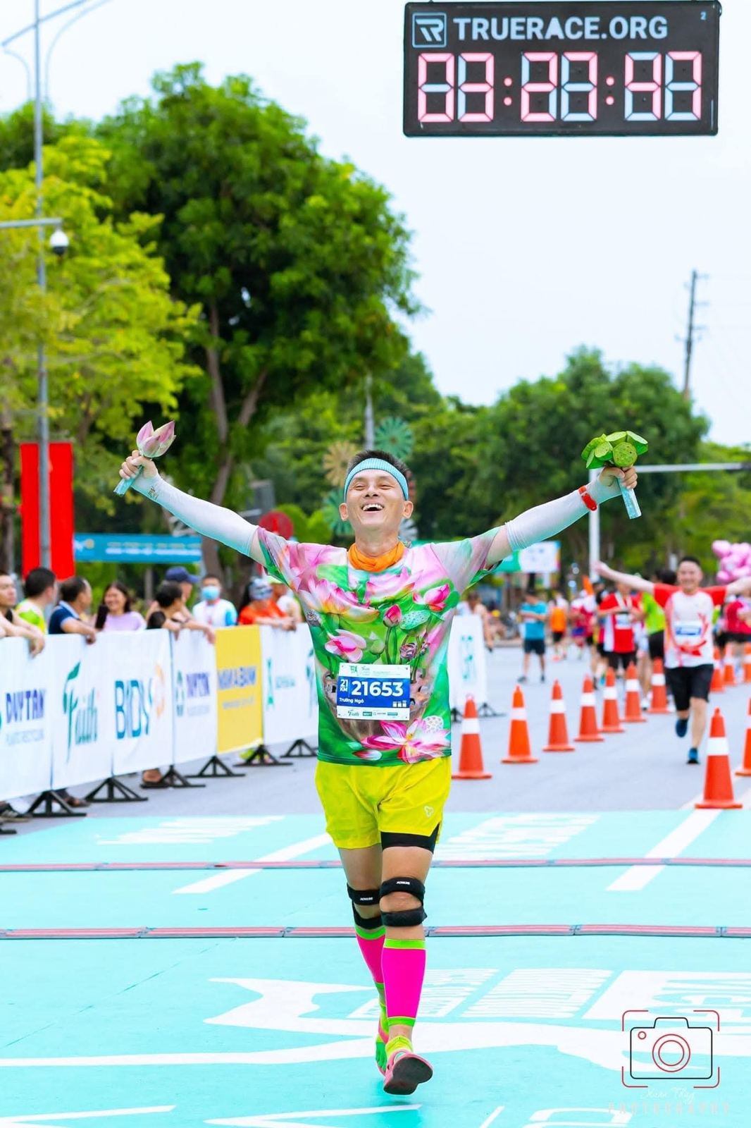 Runner raising a lotus flower at the finish under the TrueRace clock